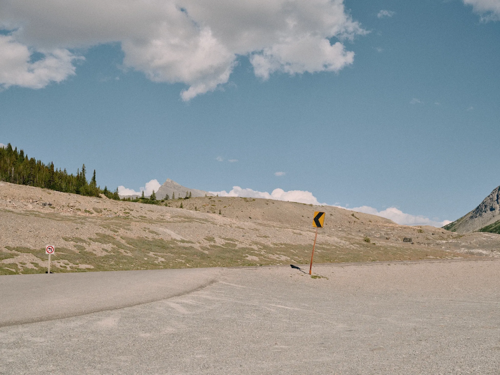 Road with an arrow pointing left and a no-left-turn sign